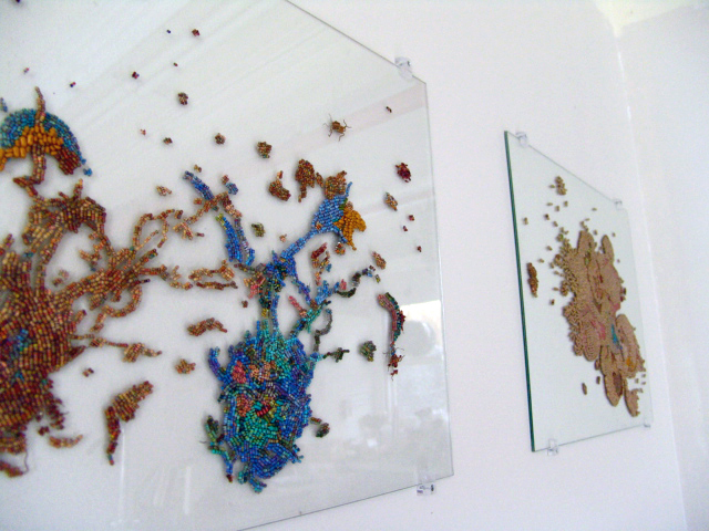 Side view of 2 glass panels on the wall, featuring images of dying cells made up of colourful electronics components.