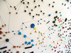 Close up of some of the capacitor 'creatures' and their relationships mapped on the wall in black ink lines.