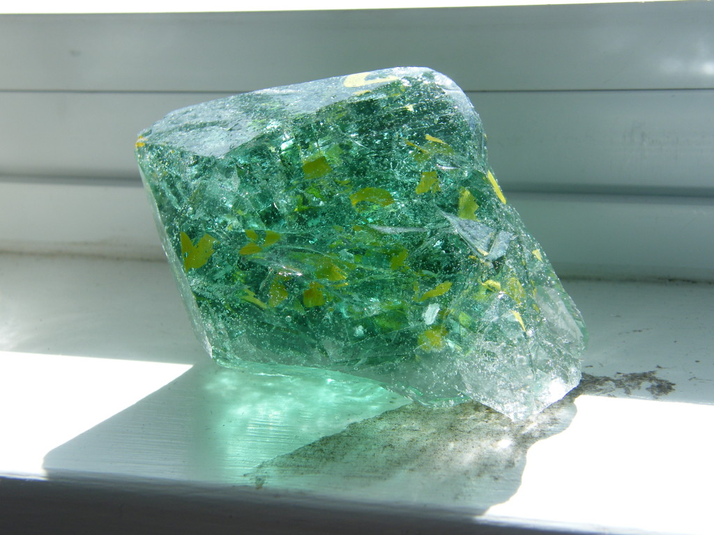 Side view of amethyst crystal cast in polyester resin and filled with green-tinted car glass with yellow paint marker.
