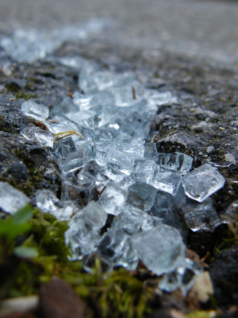 close up sidelong view of a sidewalk fissure filled with clear-white cubes of broken safety glass.